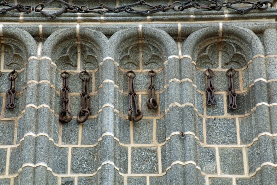 An einer schwarz eingefärbten Kirchenmauer sind die Ketten zu sehen, in den sich die aus muslimischer Gefangenschaft befreiten Christen in Toledo befanden